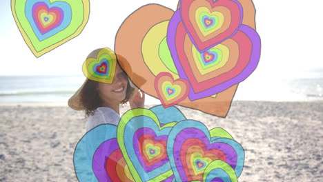 animación de corazones coloridos sobre mujer biracial caminando por la playa