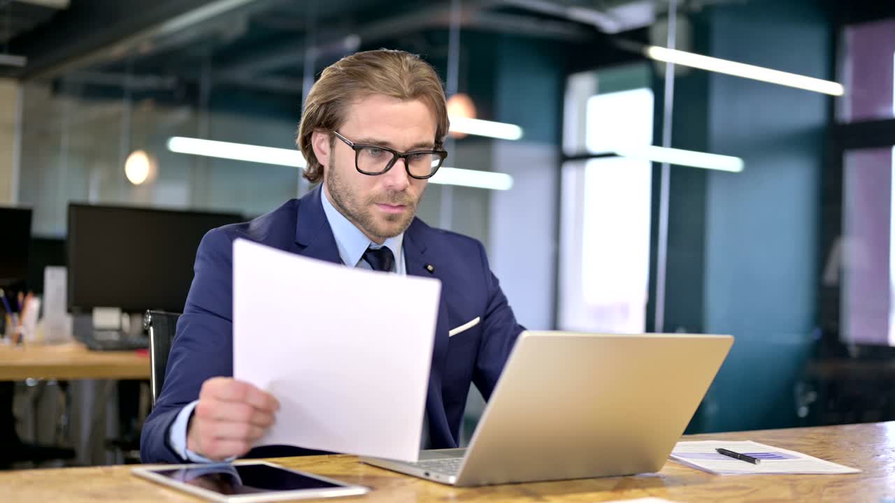 Businessman Reading Documents on Office Desk