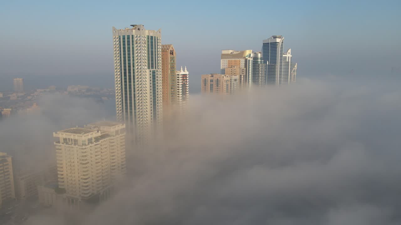 NEBBIA NEGLI EAU: Vista dall'alto di nebbia densa sull'area di Al Majaz a Sharjah, skyline di Sharjah coperto dalla nebbia mattutina invernale, Emirati Arabi Uniti, Filmato drone 4K