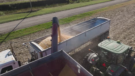 semi truck trailer being filled with grain crop harvest from a grain cart, aerial