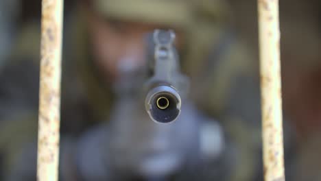 a soldier approaches with a rifle and points the barrel directly at the camera