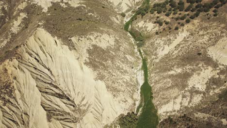 Drone-Volando-Sobre-Un-Barranco-Con-La-Cámara-Inclinándose-Lentamente-Revelando-Una-Ciudad-En-La-Cima-De-Una-Colina-En-4k