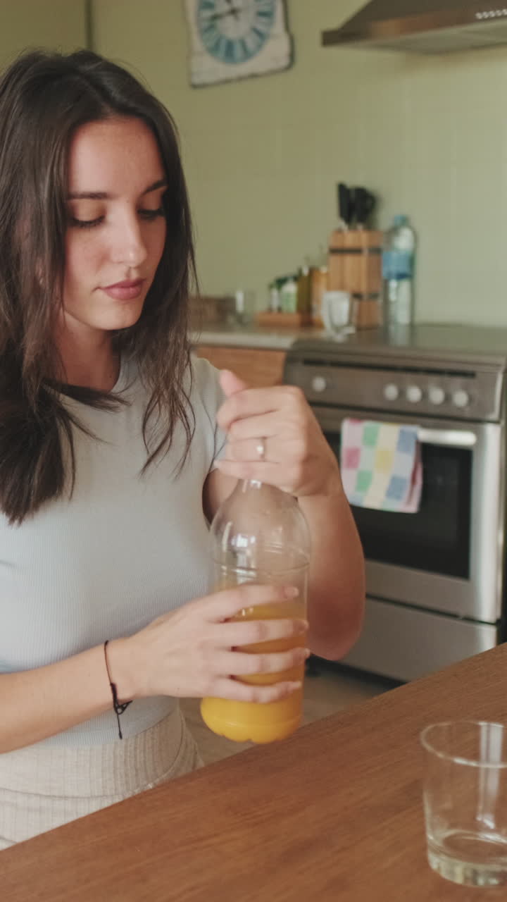 Mujer sirviendo zumo de naranja en la cocina