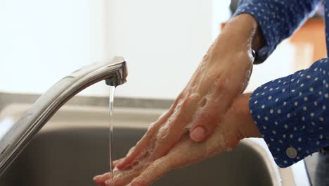 Caucasian-woman-washing-her-hands-with-soap-at-home