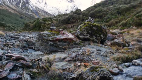 piedras del valle del río que fluye con montaña cubierta de nieve en el fondo