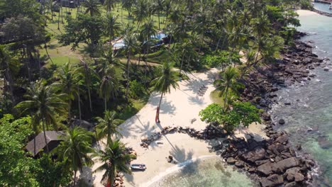 a beautiful drone shot of the tropical island of koh kood flying over koh kood beach resort and a small and charming beach surrounded by palm trees, in thailand in southeast asia