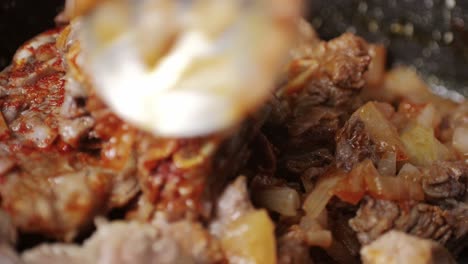 chicken or pork stew with red and green pepper onion, and spices cooking in a frying pan. traditional mexican cuisine, tacos preparation, ragout.