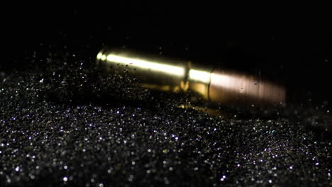 slow motion shot of cartridge firearms bullets falling on gunpowder dust, macro