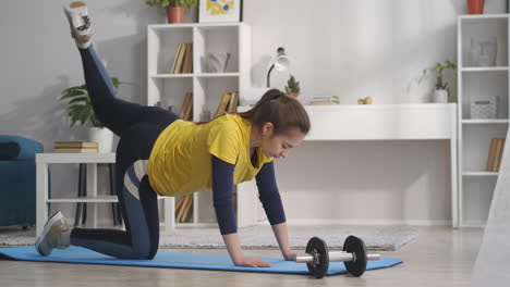 Mujer-Joven-En-Casa-Entrenando-Para-Una-Buena-Condición-Física-Y-Una-Hermosa-Figura-Levantando-La-Pierna-Ejercicio-Para-La-Parte-Posterior-Del-Muslo-Dama-Deportiva-Activa