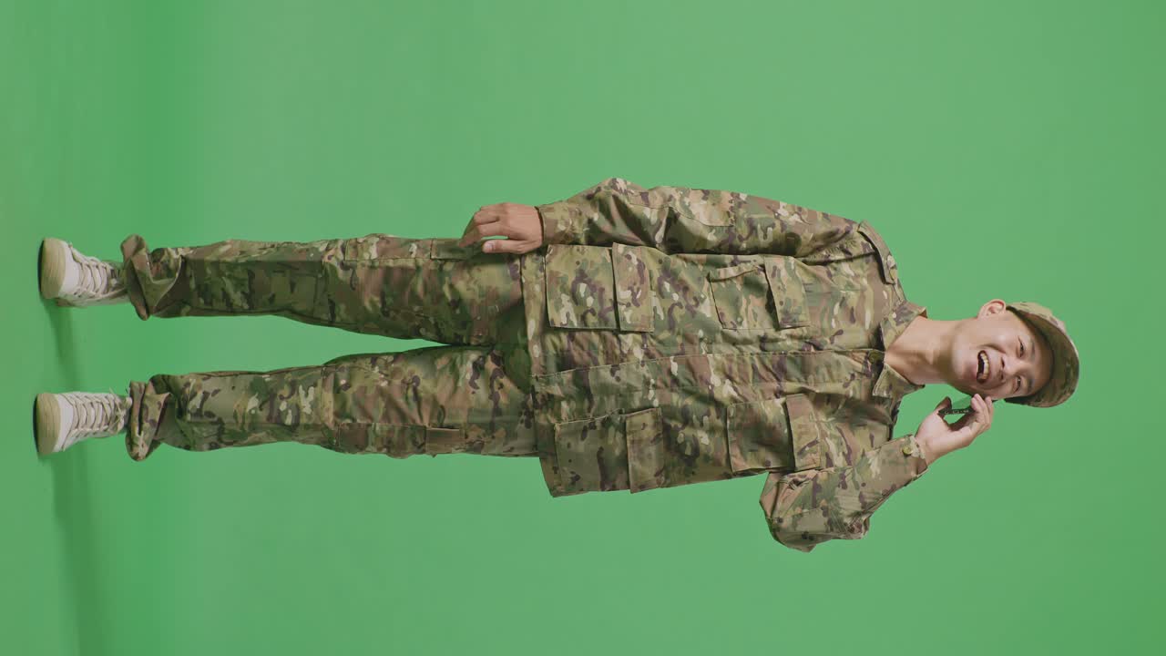 Full Body Of Asian Man Soldier Talking On Smartphone And Looking Around While Standing In The Green Screen Background Studio