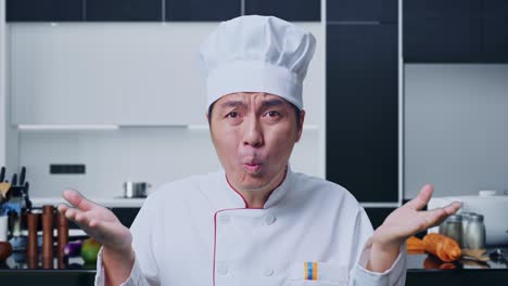 cerca de preguntarse por qué el chef asiático y de pie con dudas en la cocina de casa