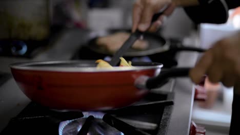 chef sou-chef preparando un plato tradicional mexicano llamado chilaquiles mezclando chips de tortilla fritos con salsa de tomate caliente en una sartén en un restaurante local de cafetería en américa latina