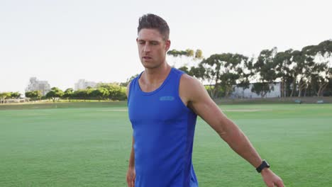 smiling fit caucasian man exercising outdoors stretching from the waist