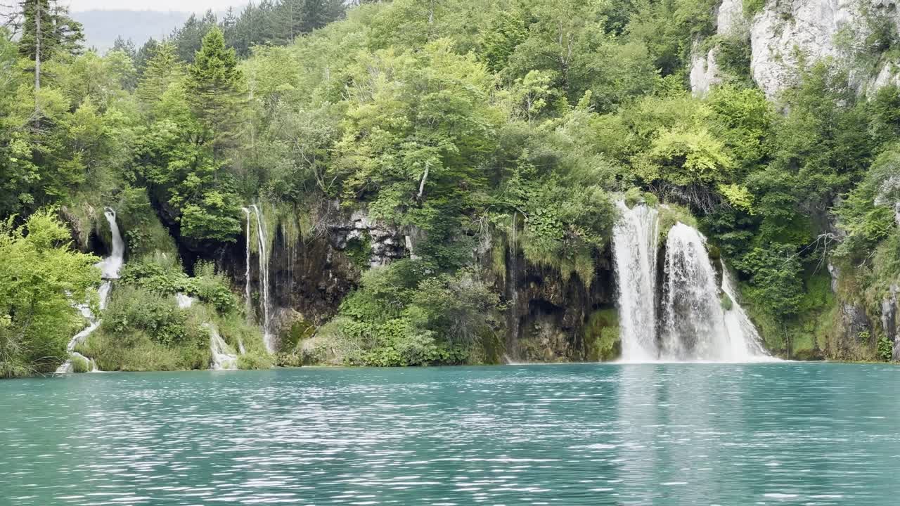 크로아티아의 플리트비체 호수 국립 공원 (plitvice lakes national park) 에 있는 아름다운 파란 호수를 가로지르는 폭포를 확대합니다.