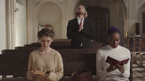 three young diverse parishioners praying in christian church