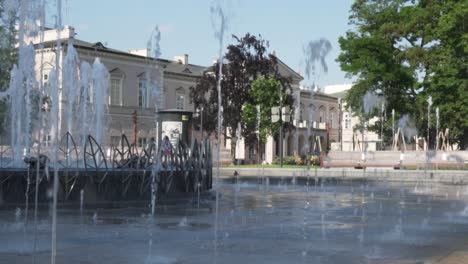 Altes-Gebäude-Mit-Strahlen-Eines-Brunnens-Im-Ersten-Semester-In-Zeitlupe-Auf-Einem-Platz-In-Polen