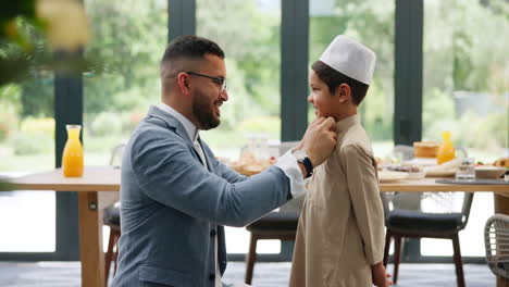 father helping son with eid outfit