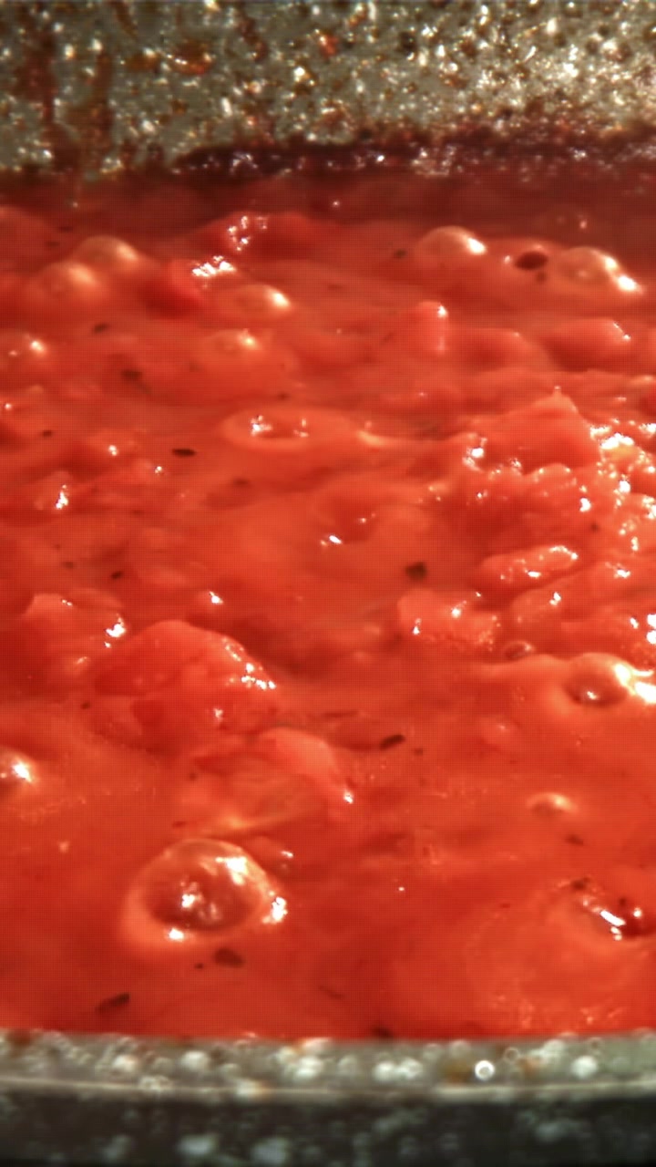 Primo piano di salsa di pomodoro rossa che sobbolle e bolle in una padella