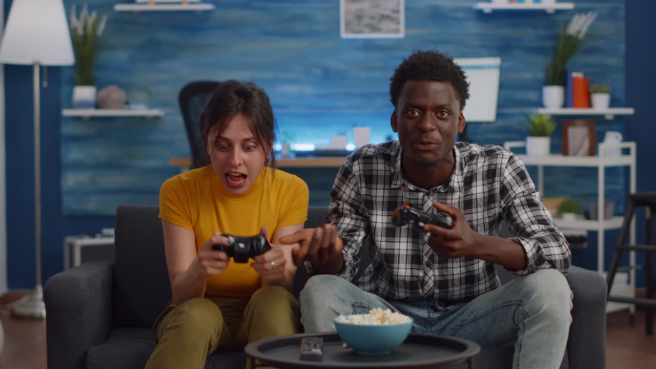 Modern interracial couple playing with joysticks for video game
