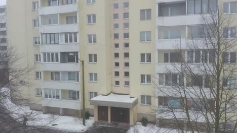 Nahe-Drohnenneigung-Nach-Oben-Eines-Gelben-Neunstöckigen-Gebäudes-Im-Sowjetischen-Stil-In-Einer-Verschneiten-Stadt