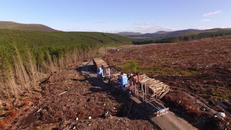 Forestry-and-logging-operations-taking-place-in-the-highlands-of-Scotland-using-large-industrial-machinery,-ships-and-trucks