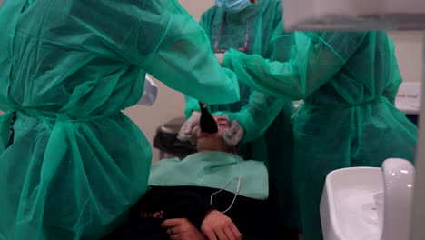 una foto borrosa de dentistas irreconocibles tomando una foto de los dientes de un paciente joven