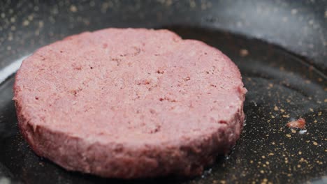 plant-based burger patty frying in a pan