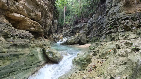 deep natural gorge with fresh river stream flowing in bottom - static slow motion aerial philippines