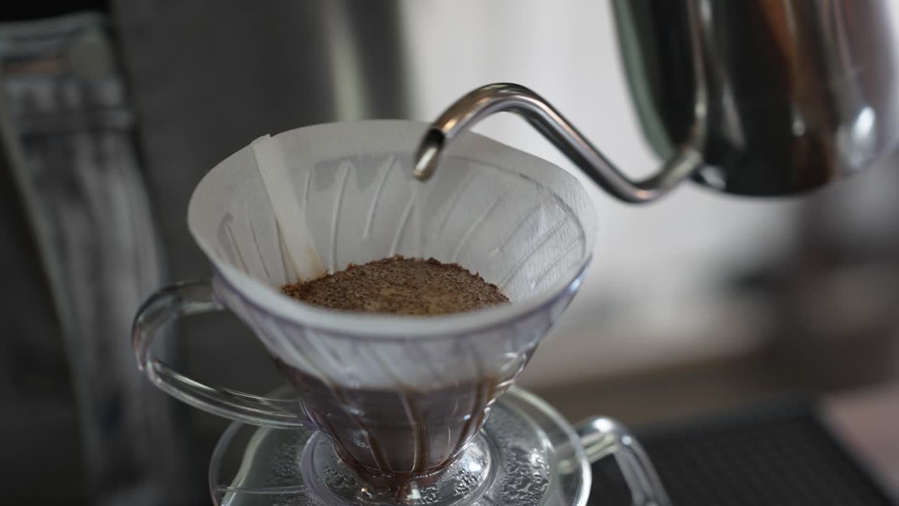 A barista prepares a pour over coffee with a controlled water pour
