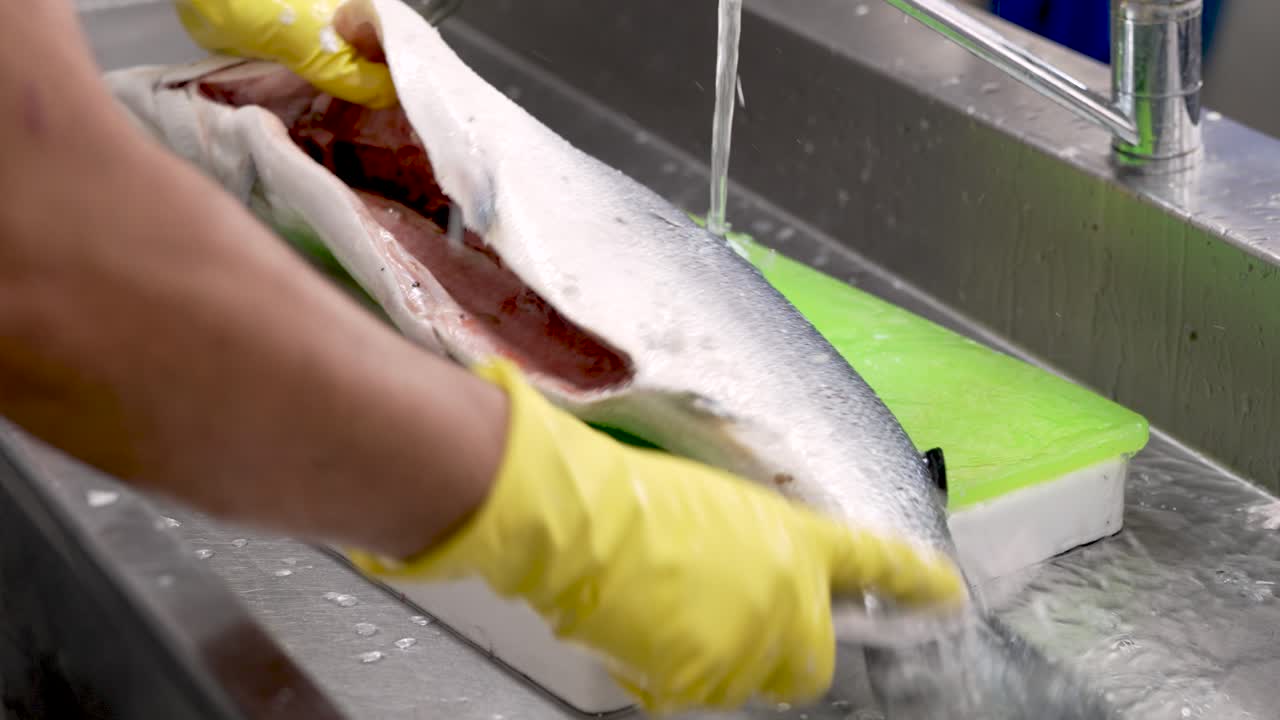 A skilled chef deftly cleans a fresh fish at a vibrant culinary workspace, showcasing techniques in fileting and preparing seafood for an upcoming dish