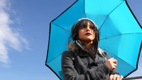 una hermosa mujer con cielo azul y paraguas meteorológico mientras las nubes de lluvia de una tormenta pasan por encima en cámara lenta