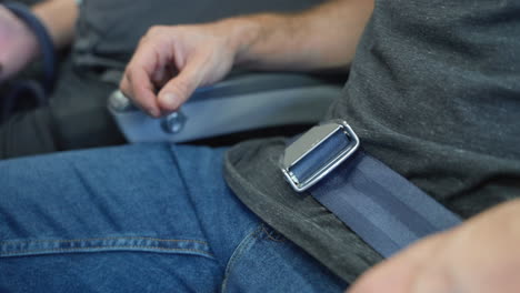 Close-up-on-airplane-seat-belt-unbuckled-by-man-as-he-gets-up-from-his-seat-after-landing-or-during-flight