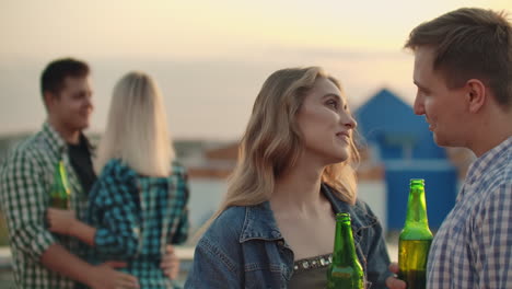 dos parejas enamoradas hablando con sus almas gemelas en la fiesta. disfrutan del tiempo juntos con cerveza en el techo.