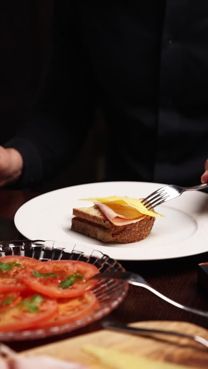 Hand Cutting a Ham and Cheese Sandwich on a Plate