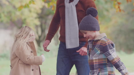 boy and girl playing and having fun with parents throwing autumn leaves in garden