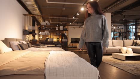 gorgeous young woman smiling examining orthopedic mattress on sale at big furniture store gorgeous young woman smiling examining orthopedic mattress on sale at big furniture store high quality footage