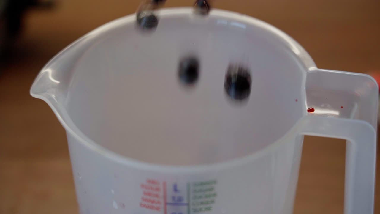 высокий угол крупного плана замороженных ягод, падающих из купленного в магазине пластикового мешка в литровую меру в замедленном движении