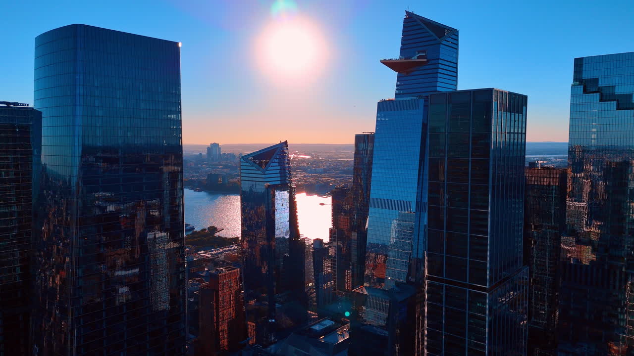 Arranha-céus modernos de vidro em Manhattan ao pôr do sol com reflexo solar. Vista aérea de altos edifícios de escritórios de vidro e deck de observação triangular durante a hora dourada na cidade de Nova Iorque.