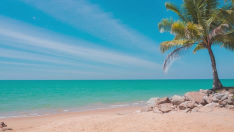 timelapse of sea waves crashing on sandy beach. coconut trees and rocky beach. blue sky with cirrus clouds sprayed over clear wide space. panoramic aerial veiw of sea. traveling to thailand in summer