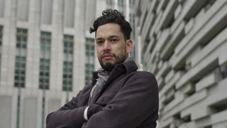 portrait of successful young entrepreneur, dressed in autumn clothes, looking at camera serious strong, outdoors in downtown business district