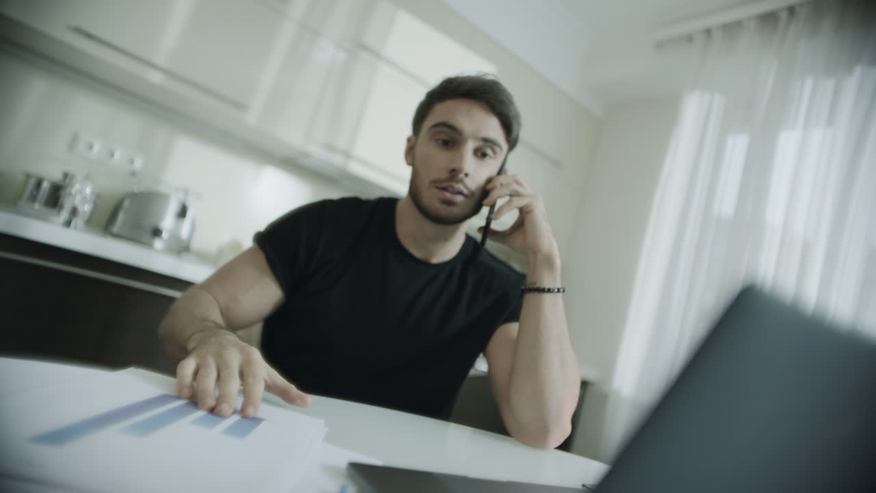 Angry business man talking mobile phone at home. Furious person throwing papers
