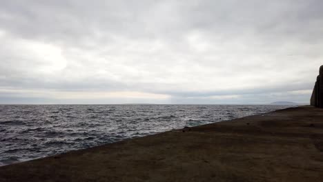 lapso de movimiento de ángulo bajo de nubes grises rodando sobre el océano en el paseo marítimo de ciudad del cabo