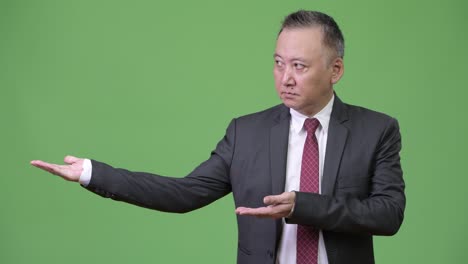 mature japanese businessman showing something