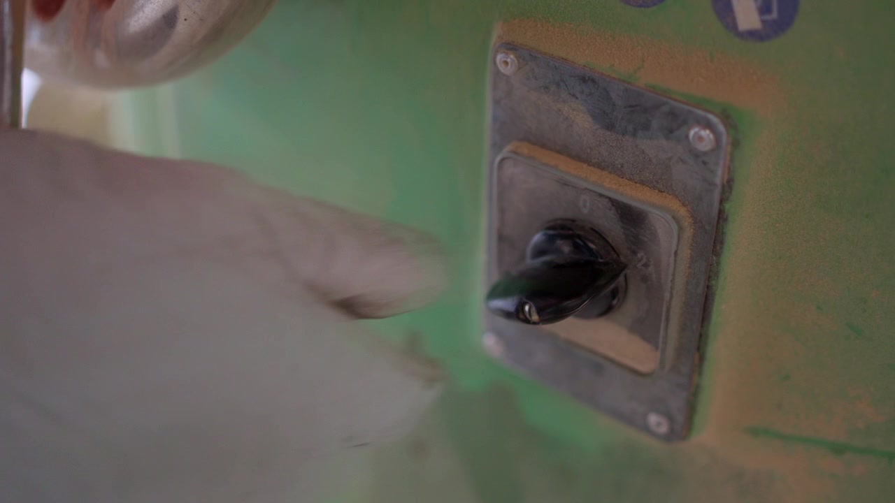 Worker turning a dusty industrial power switch