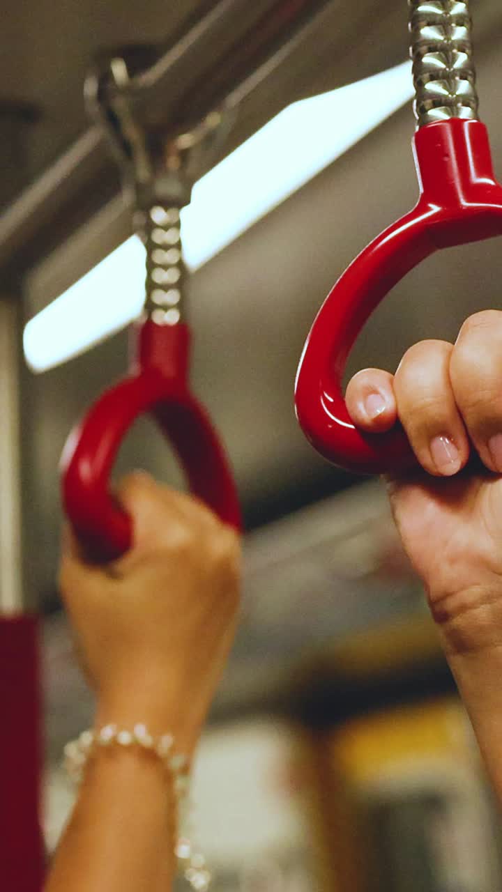 Mano che si tiene a un maniglione del treno in movimento.