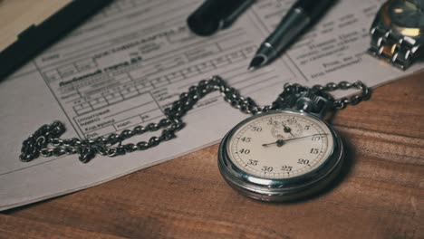 un cronómetro antiguo yace en un escritorio de madera con documentos viejos y cuenta segundos.