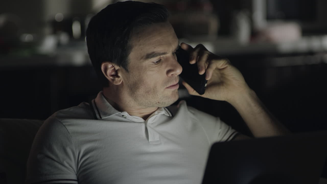 야간 사무실에서 전화 통화 중에 비명을 지르는 화난 남자의 클로즈업.