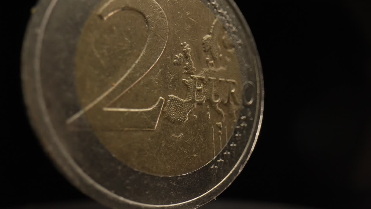 primer plano de una moneda de 2 euros con un fondo negro que está girando
