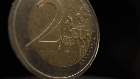 close-up of a 2 euro coin with a black background that is spinning