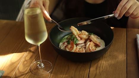 mujer comiendo un plato de camarón con vino en un restaurante